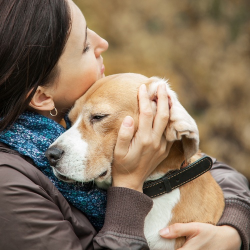 A woman and her dog share a warm hug